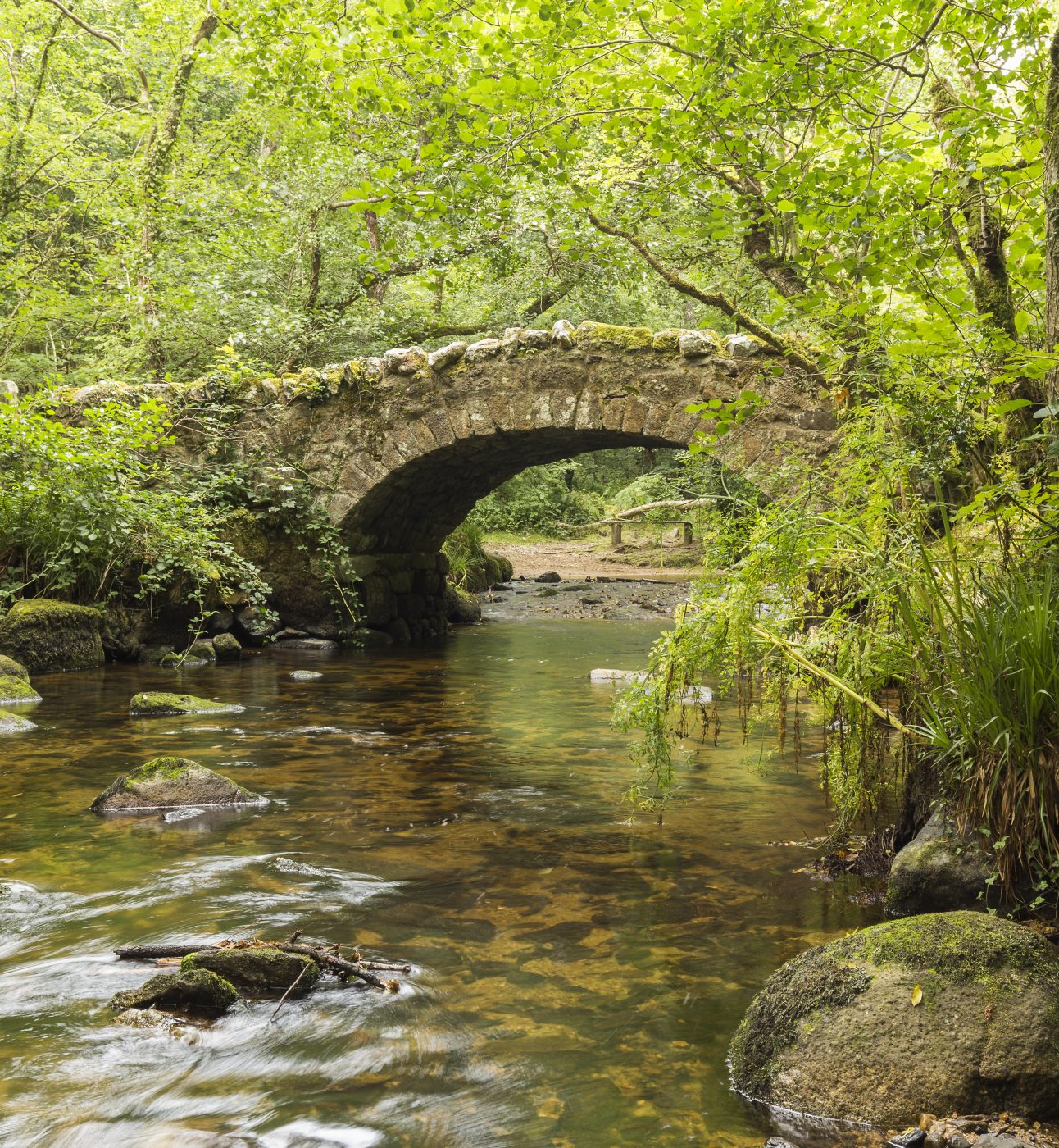 A riverside image of Hisley Bridge an old packhorse bridge over the river Bovey, shot at Dartmoor, Devon, England, UK